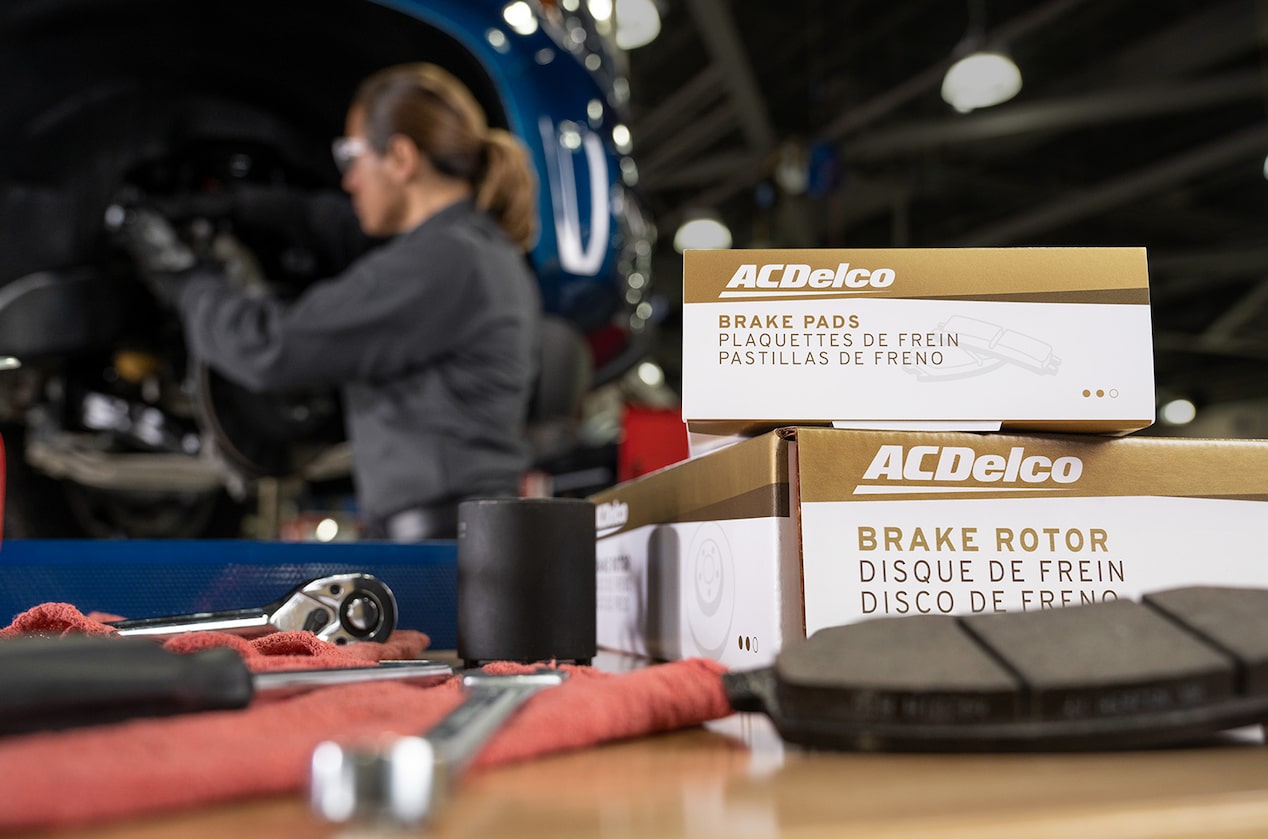 Two Premium Gold ACDelco Boxes on a Table with a Woman Working In the Distance