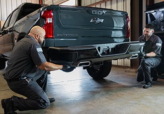 A Service Technician Working on the Rear Side of a GMC Truck