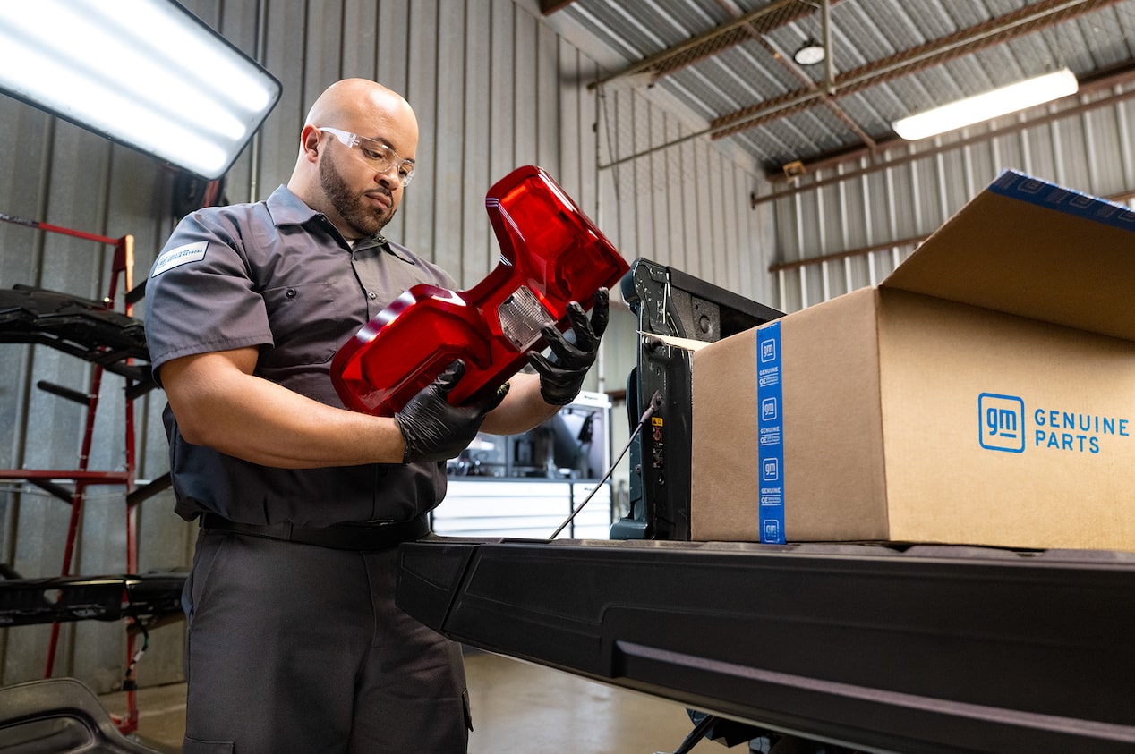 A Technician Holding Up a GM Vehicle Part