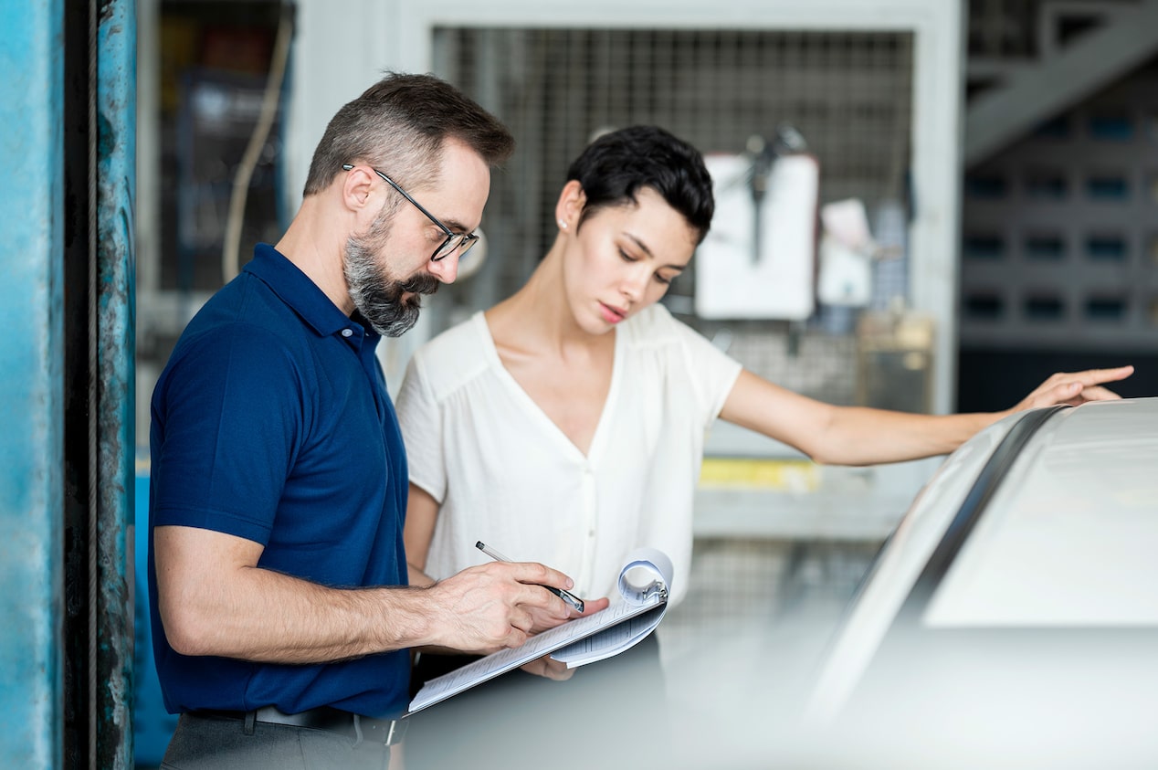 A Man Looking Over a Paper with a Woman Standing Next to Him