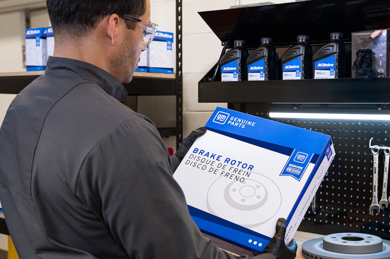 A Technician Holding Up a GM Vehicle Part