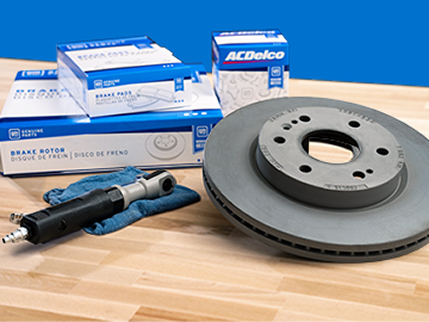 A Disc Brake Rotor is Shown on a Table Next to a Stack of ACDelco GM Genuine Parts Boxes.