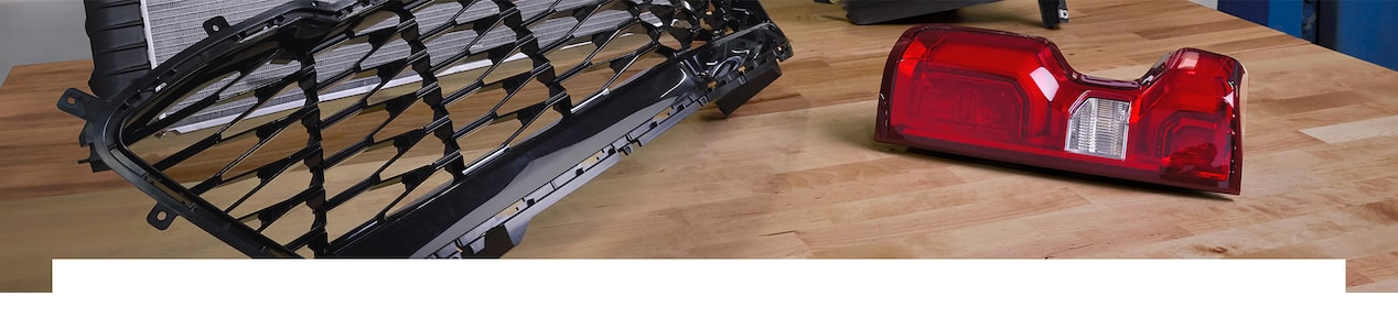 A Mechanic Holding a Headlight While Standing in Front of a Tire that is Laying on the Ground