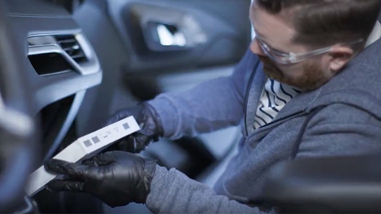 A Video Thumbnail of a Mechanic Inside the Front Seat of a Vehicle Performing an Inspection.