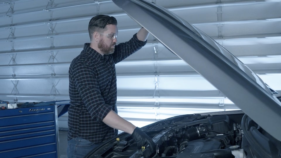A Mechanic is Observing the Engine of a Vehicle Holding its Hood Open