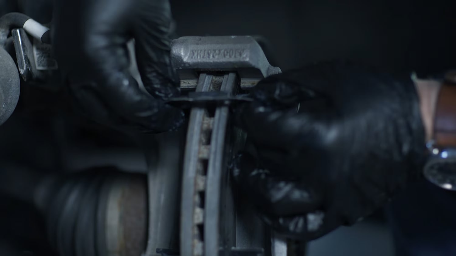 A Person with Black Gloves Working on the Brake System of a Vehicle
