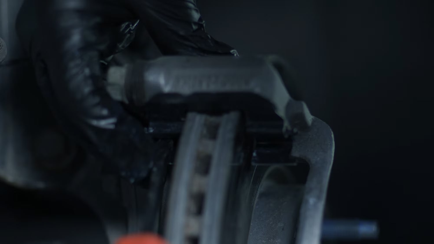 A Person with Black Gloves Working on the Brake System of a Vehicle