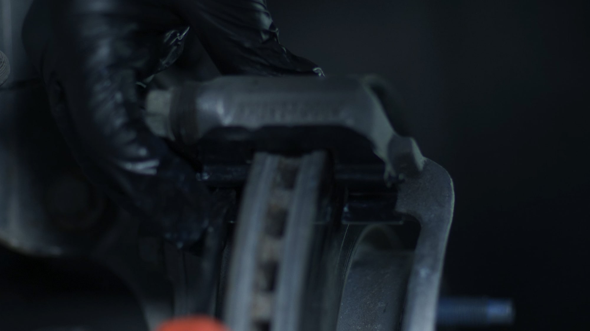 A Person with Black Gloves Working on the Brake System of a Vehicle