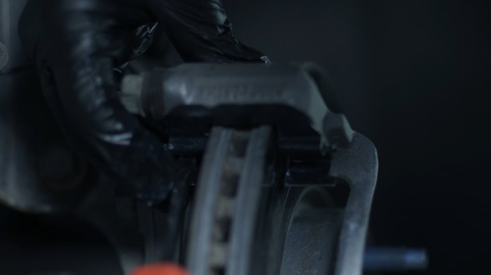 A Person with Black Gloves Working on the Brake System of a Vehicle
