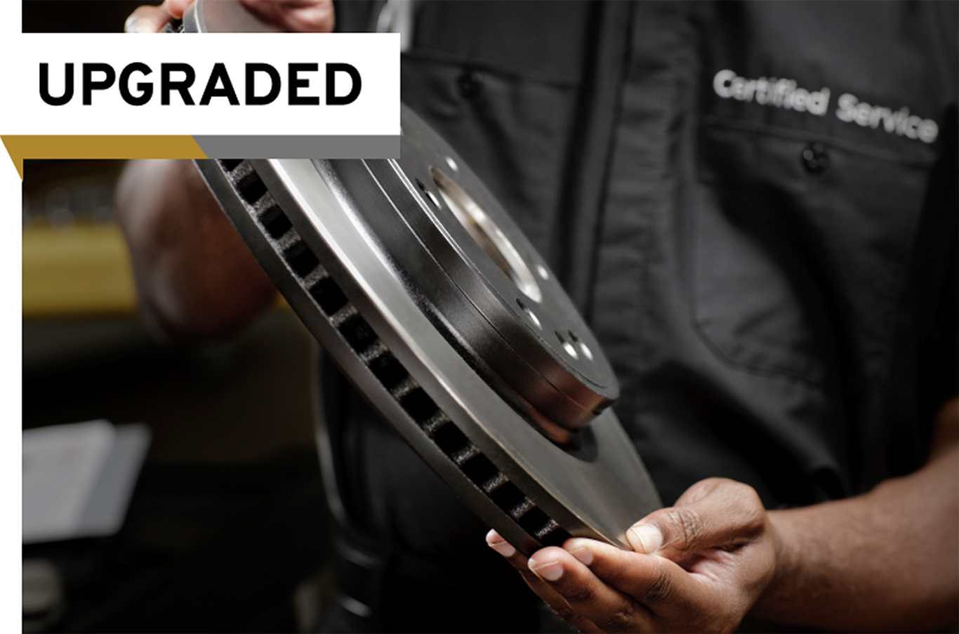 A Certified Service Technician Holds an Improved Disc Brake Rotor With an "Upgraded" Label on the Image.