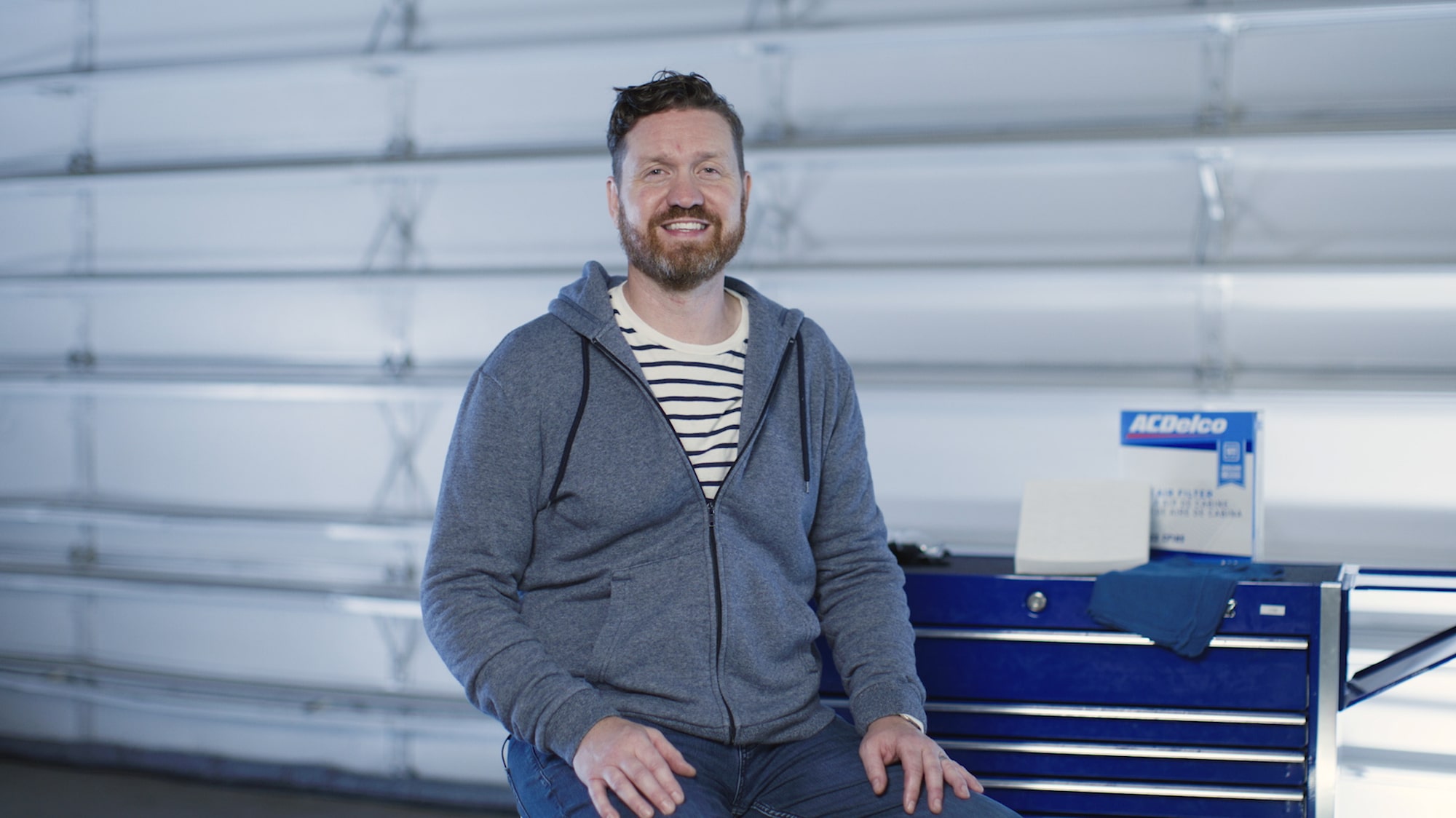 A Man Sitting Next to a Work Bench.