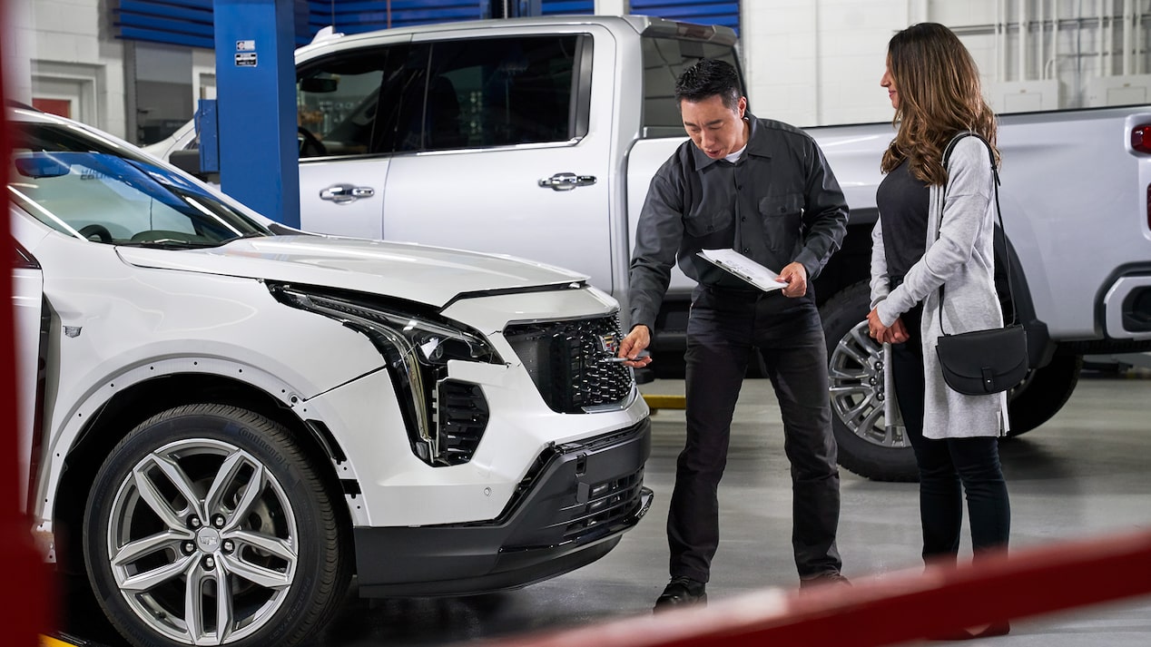 A Technician and a Woman Inspecting the Front of Her Vehicle
