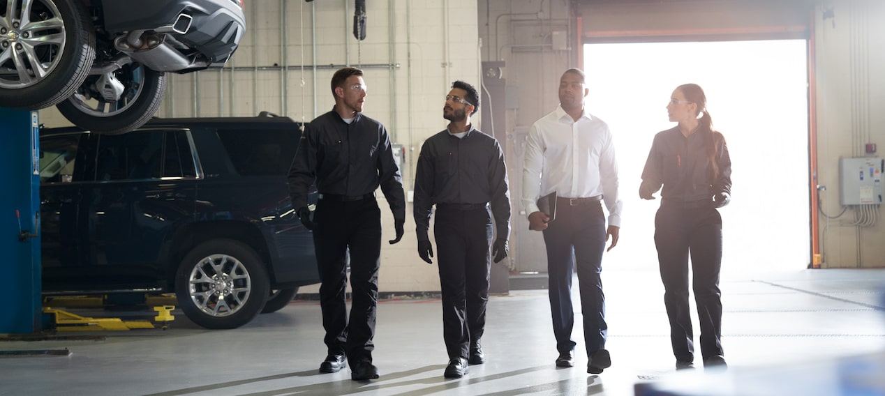 Group of Technicians Walking with a Business Professional in a Vehicle Service Bay