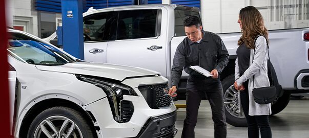 GM Technician Pointing to a Vehicle's Grille While Having a Discussion with a Customer