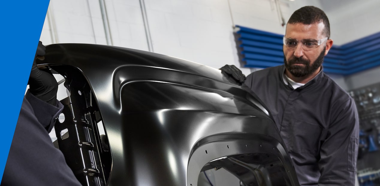 A Mechanic Wearing Safety Glasses Holding a Metal Frame for a Vehicle