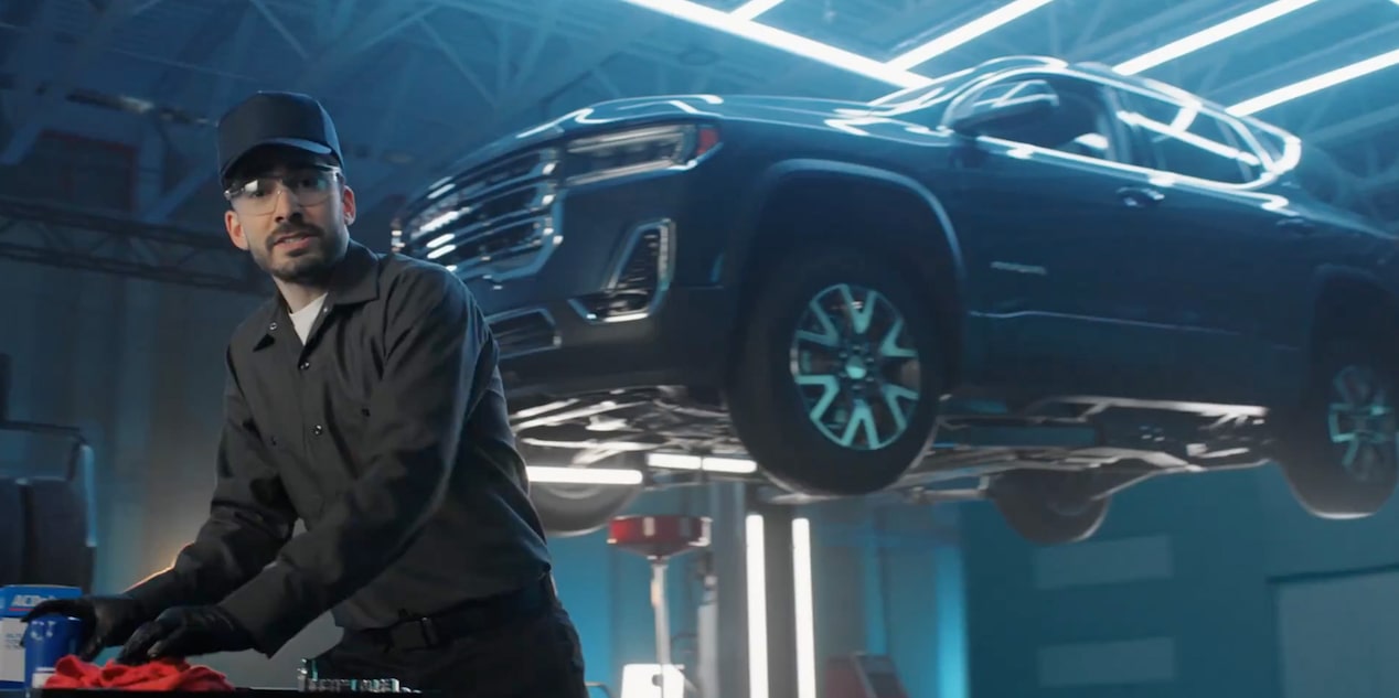 Video Thumbnail of a Mechanic Working While a Vehicle Is Suspended in Air Behind Him