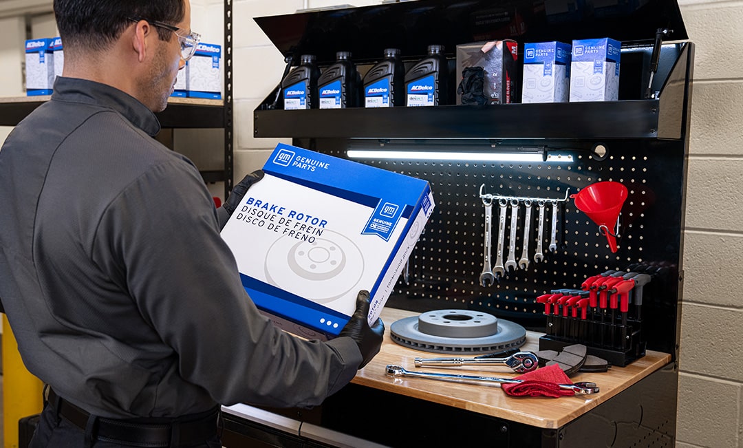 A Man Wearing Gloves Looking at an ACDelco Brake Rotor Package