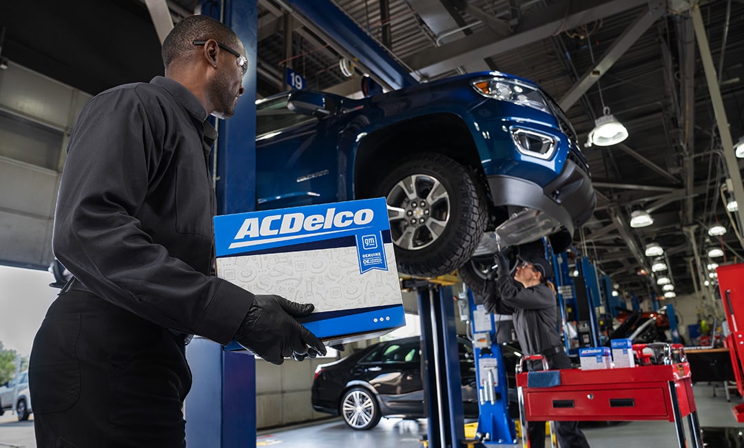 A Mechanic is Walking with an ACDelco Package in a Garage
