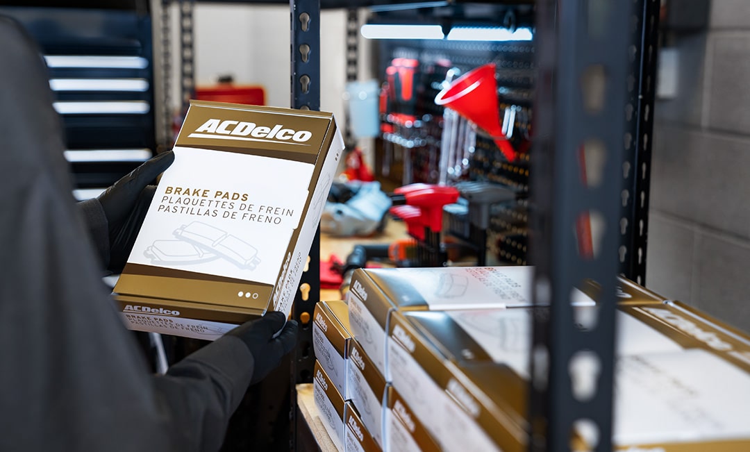 A Person with Gloves Holding a Package of ACDelco brake Pads