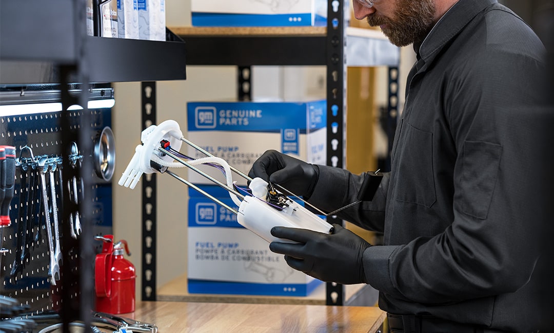 A Mechanic is Seen Wearing Gloves and Holding a White Fuel Gas Pump