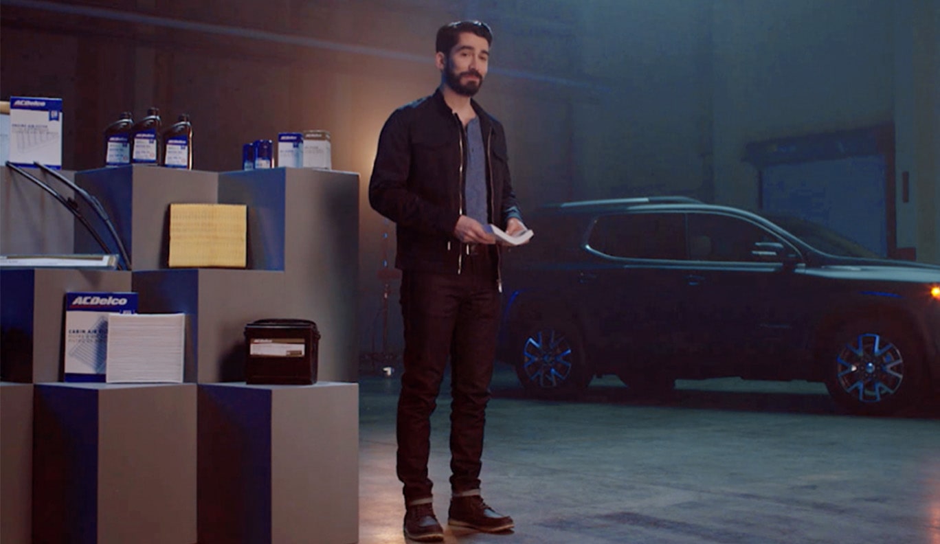A Man Standing Next to an ACDelco Parts Display With a Vehicle in the Background