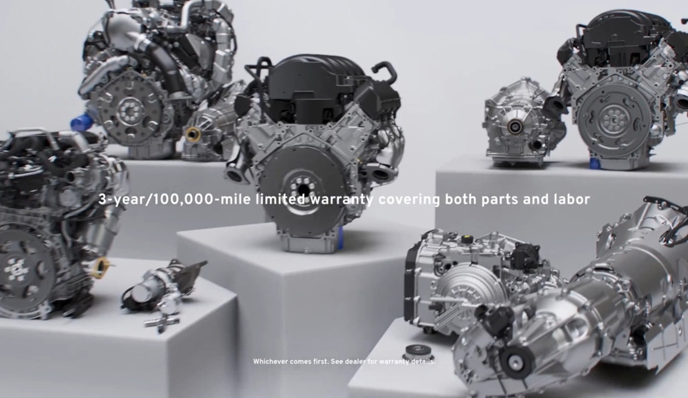 Various GM Genuine Engines Sitting on Display with Text Overlay "3-year/100,000-mile limited warranty covering both parts and labor"